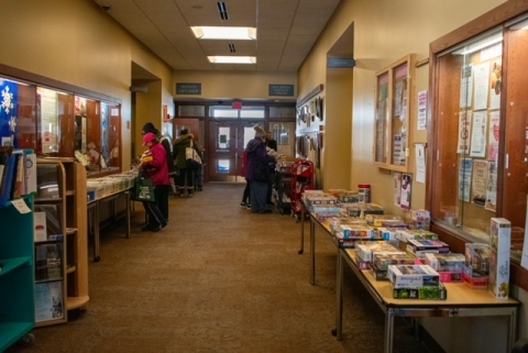library hallway with table on each side filled with books and puzzles