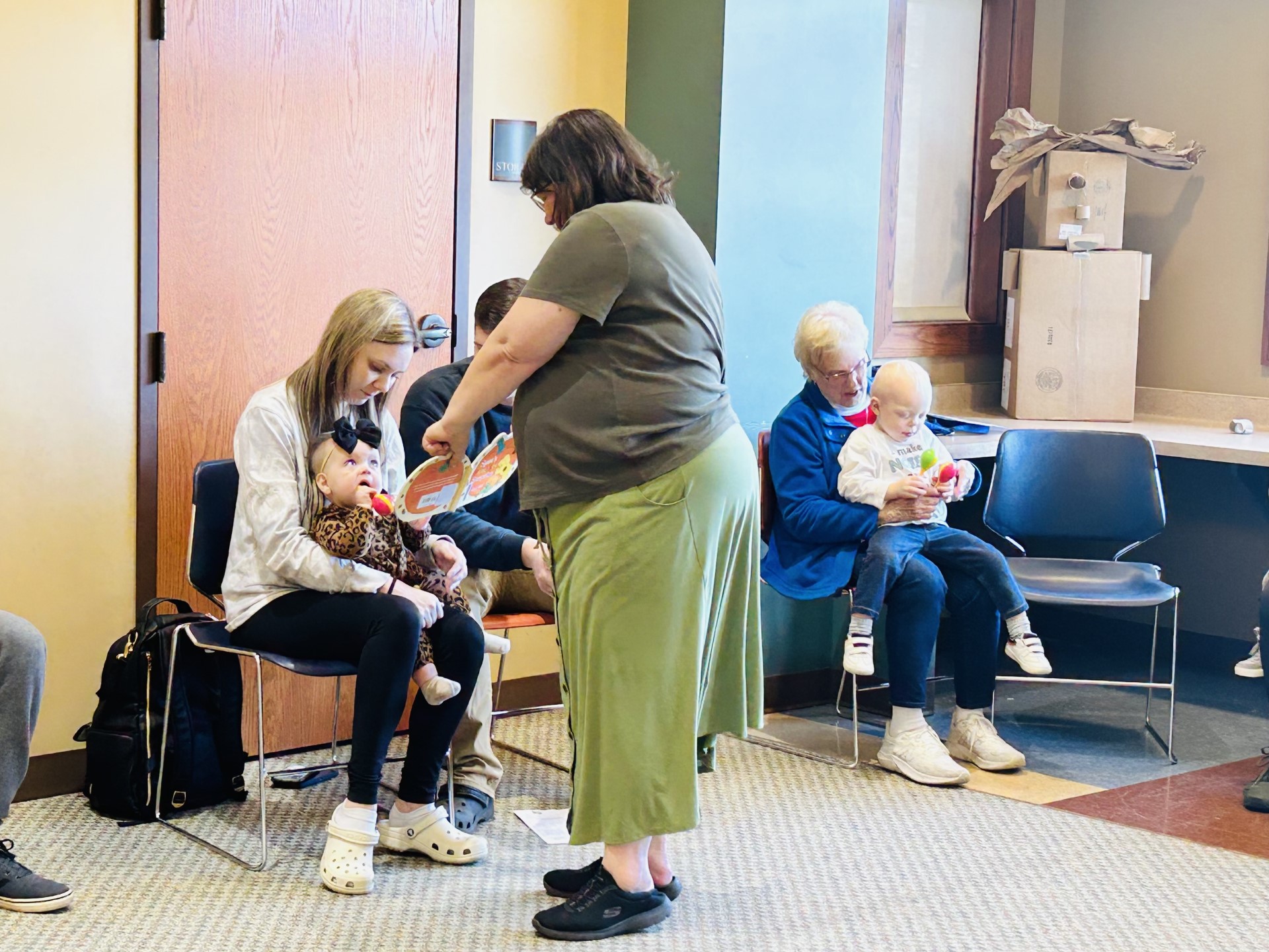 Librarian showing a book to baby and parent