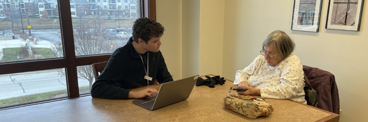 Photo of a librarian assisting a woman one-on-one with a smartphone and laptop