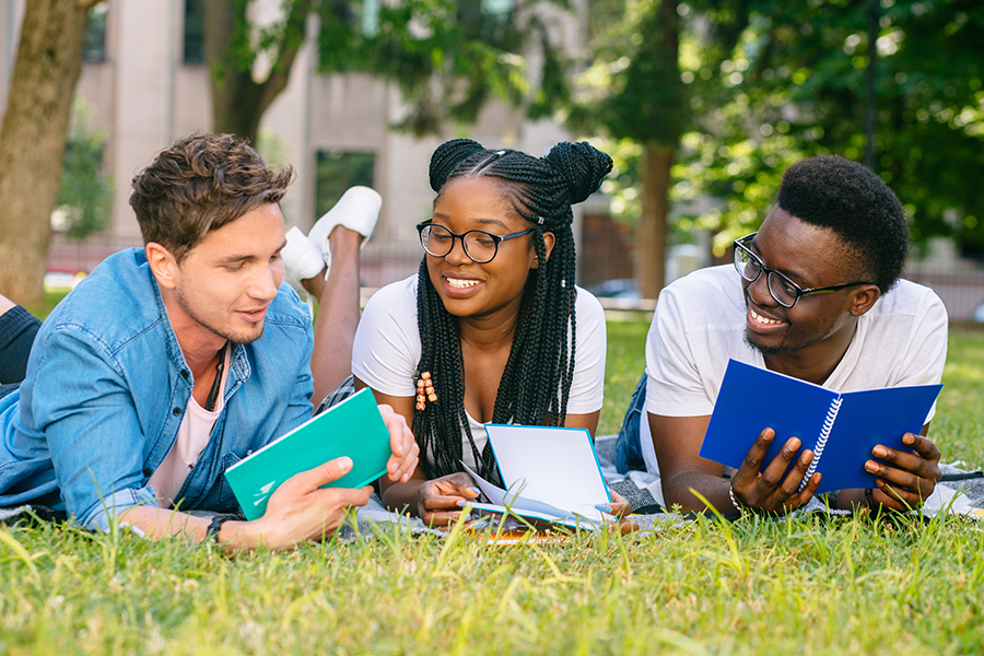 Three teens smiling and looking at books