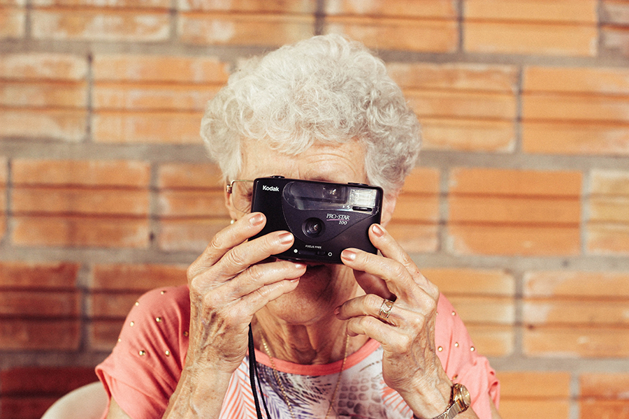 Senior woman smiling and taking a picture with a camera