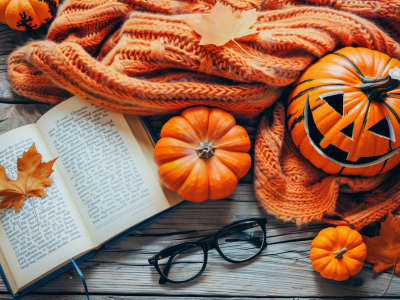 Open book with Jack-o-lantern, orange blanket, and fall leaves