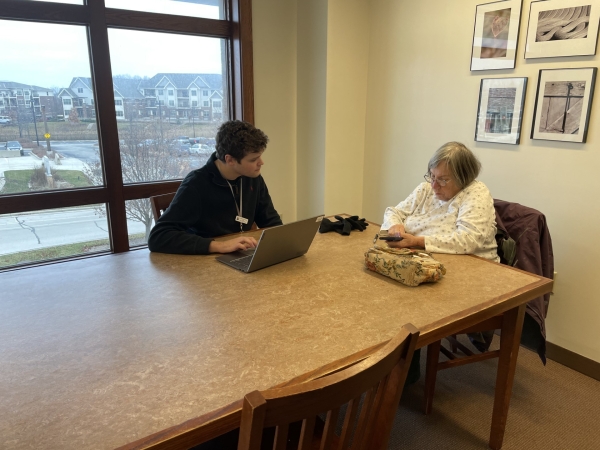 Photo of a librarian assisting a woman one-on-one with a smartphone and laptop
