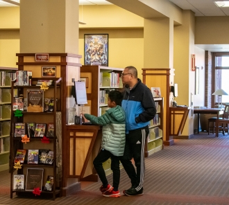 Two people using the catalog computer in the library