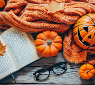 Open book with Jack-o-lantern, orange blanket, and fall leaves