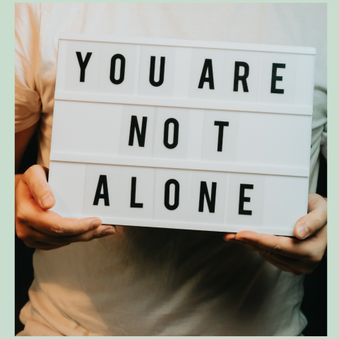 image of a person holding a sign that says "you are not alone"