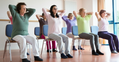 adult women stretching in yoga positions in chairs