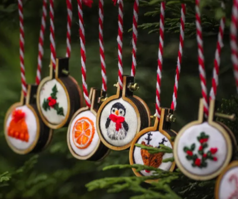 ornaments hanging from colored thread with images of holly, oranges, penguin, reindeer and snow hat