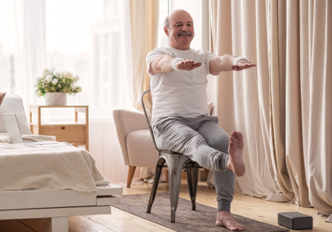 Elderly man doing a yoga stretch in a chair