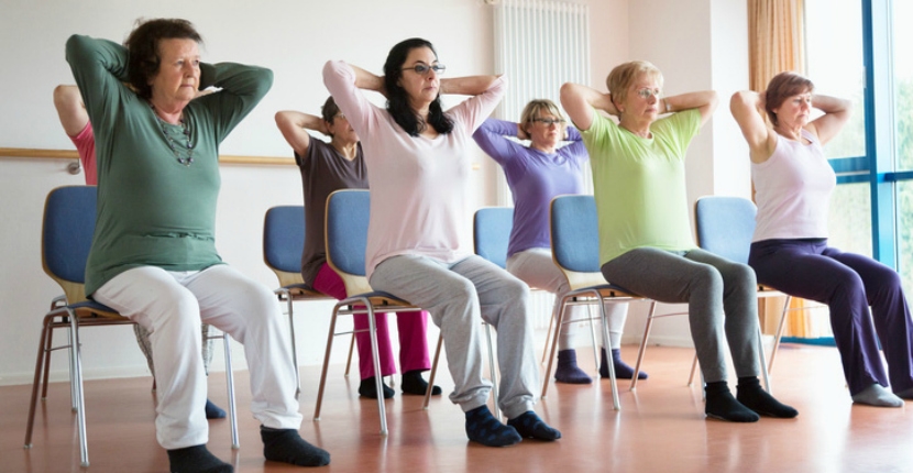 adult women stretching in yoga positions in chairs