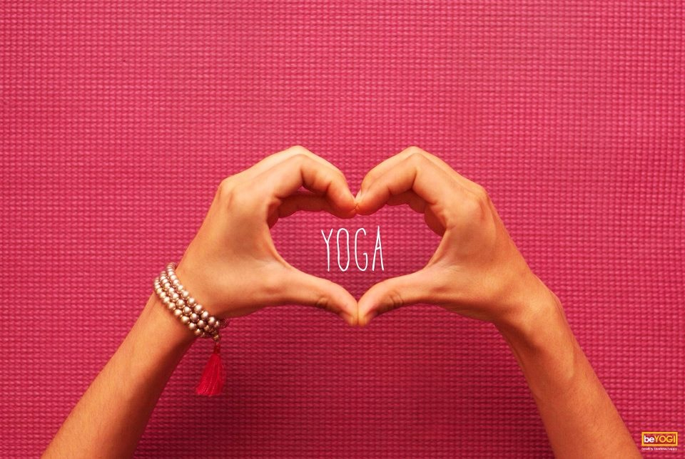hands bent to form a heart with the word yoga in the center, pink background