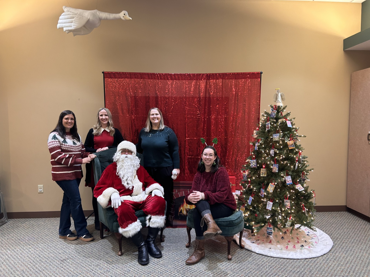 Librarian's taking picture with Santa in front of tree