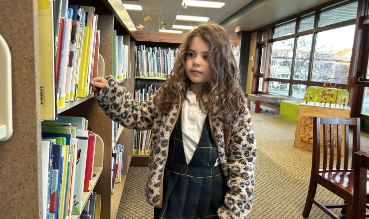 Young girl browsing the library stacks in the Children's Department
